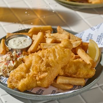Photo of fish and chips with a lemon wedge being squeezed