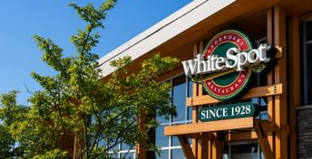 Legendary WhiteSpot Restaurant sign on wooden building exterior with trees and clear blue sky, established since 1928