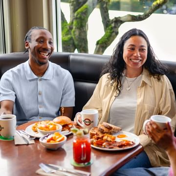 Photo of three friends sitting in a booth sharing food
