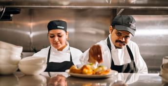 Two back-of-house team members are preparing food in the kitchen