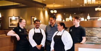 White Spot team members standing together inside a White Spot restaurant for a group photo.