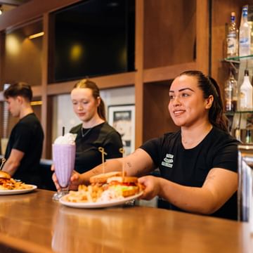 Team members serving guests food from behind the bar.