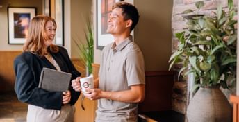 Photo of two office team members laughing and chatting with each other.